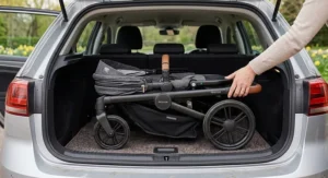A compact folded travel system pushchair chassis lying flat inside a UK family hatchback car boot, demonstrating space-saving storage.