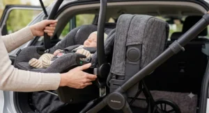 An i-Size infant car seat being clicked onto a travel system pushchair frame using quick-release adaptors for easy car-to-stroller transition.