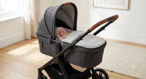 Newborn lie-flat carrycot attachment fitted onto a travel system pushchair chassis, showing the soft padded lining and protective apron for a baby from birth.