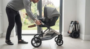 Parent demonstrating the quick-fold mechanism of a travel system with car seat chassis.