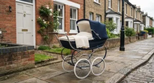 A smart navy blue classic pram for a newborn parked outside a traditional terraced house.