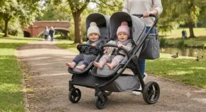Twin babies comfortably seated side by side in a double buggy during a walk in a British park