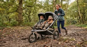 Double off road jogging stroller navigating a muddy woodland trail with suspension active