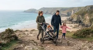 A family walking along a coastal path near a beach using a sturdy off-road pushchair