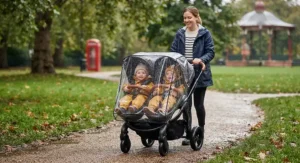 A high-end double pram equipped with a clear rain cover protecting twins from British weather.