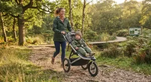 Smiling parent pushing an all-terrain off road jogging stroller through a local nature reserve