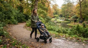 A lightweight pushchair under £100 being wheeled along a muddy autumn park path