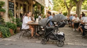 Travel system pram for newborn twins with car seats attached outside a local café