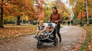 A versatile double pushchair under £300 being manoeuvred along a muddy autumn path in a British park